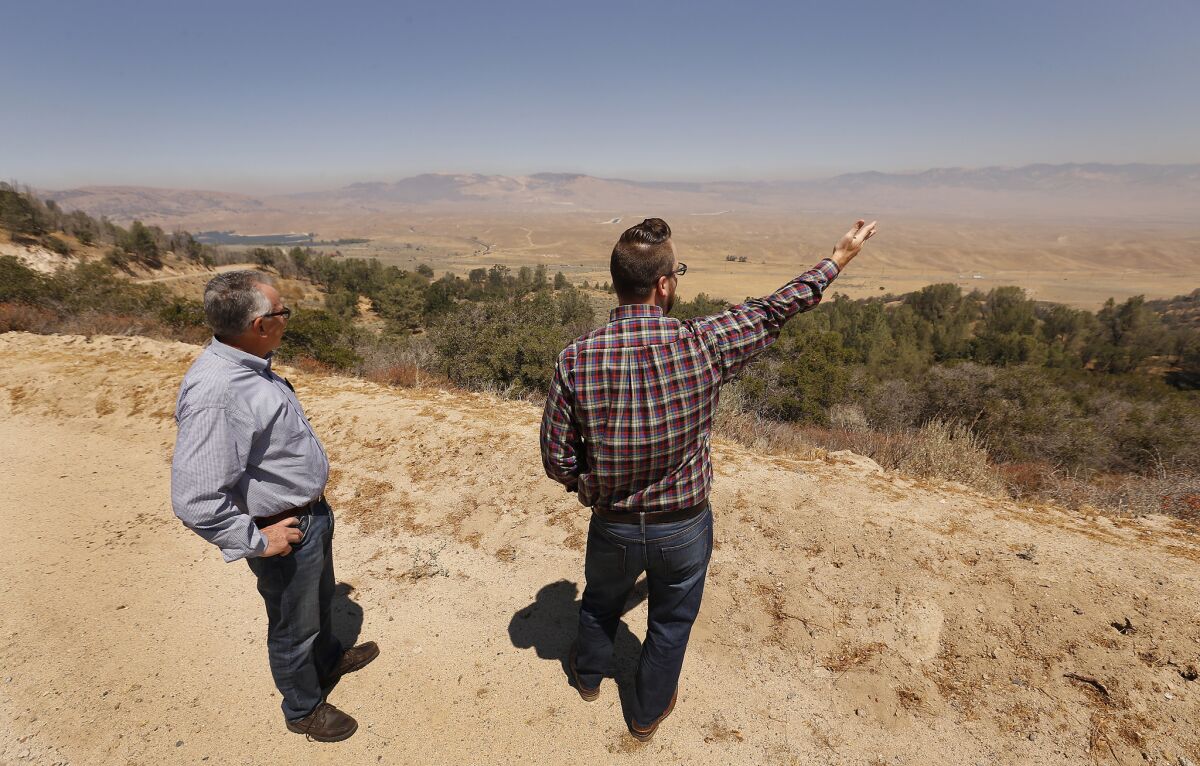 Greg Medeiros, left, and Nathan Keith point to the Blue Ridge Range backdrop. If approved, the 12,000-acre proposed master planned community named Centennial would bring in up to 19,333 residences.