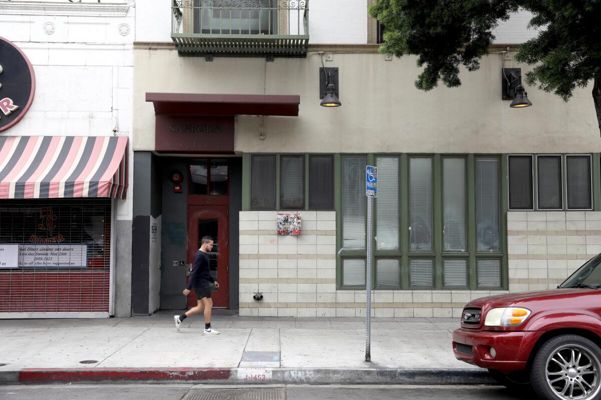 A pedestrian passes a doorway on  a city sidewalk.