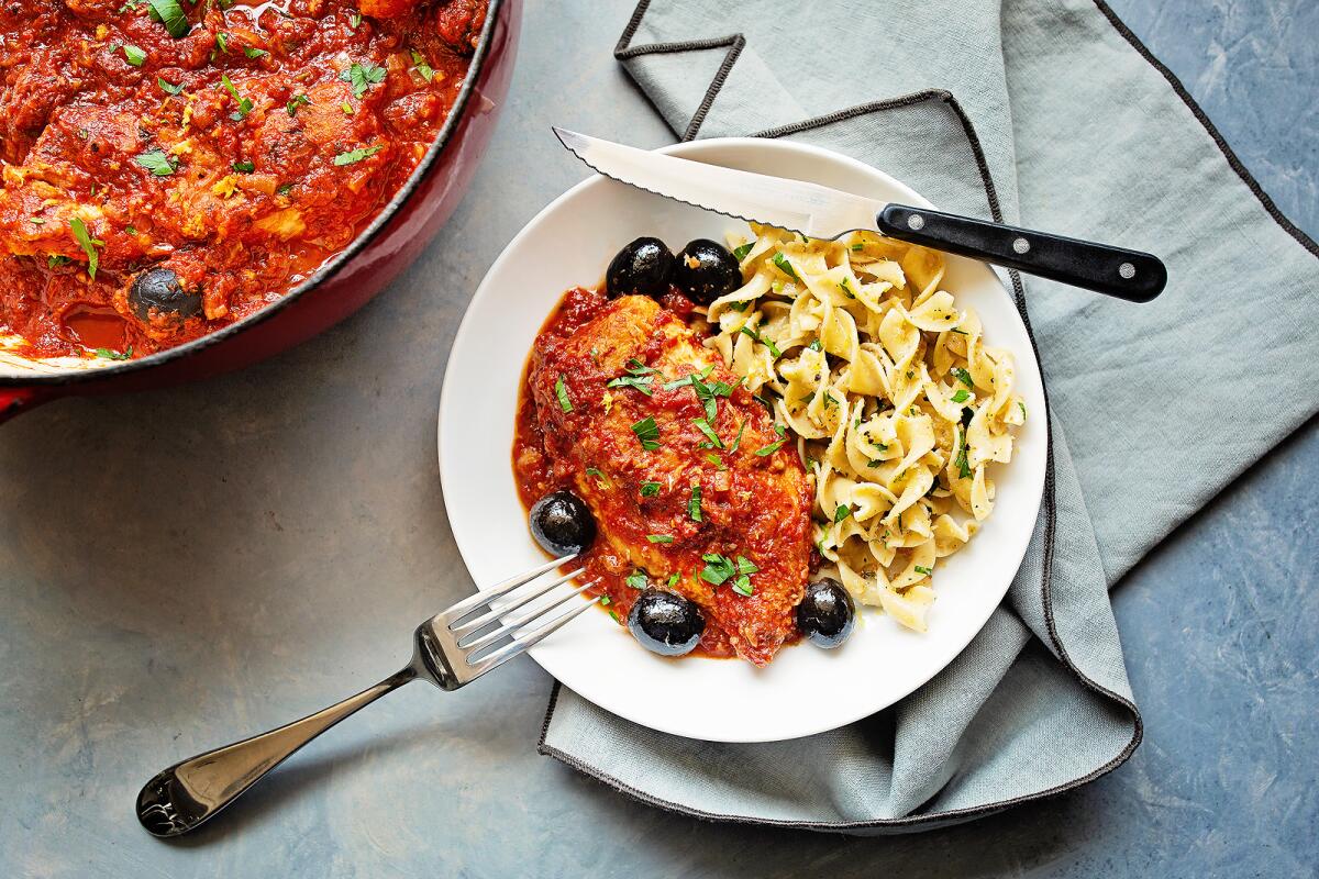 Chicken Provençal with tomatoes and olives is served with noodles.