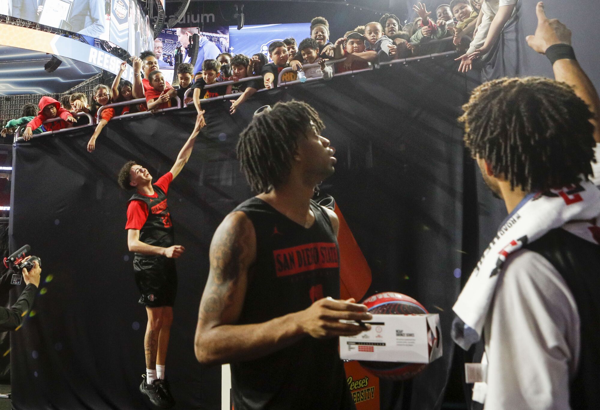San Diego State guard Miles Byrd (21), left, leaps for high fives as teammates sign autographs after practice.