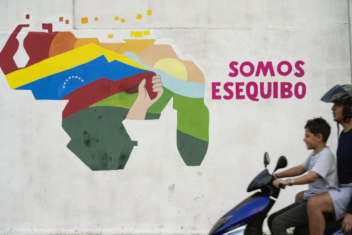 A boy drives a motorcycle in front of a map of Venezuela that includes the disputed Essequibo territory.