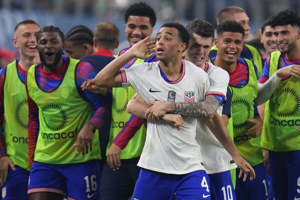 U.S. midfielder Tyler Adams celebrates with Christian Pulisic and other teammates.