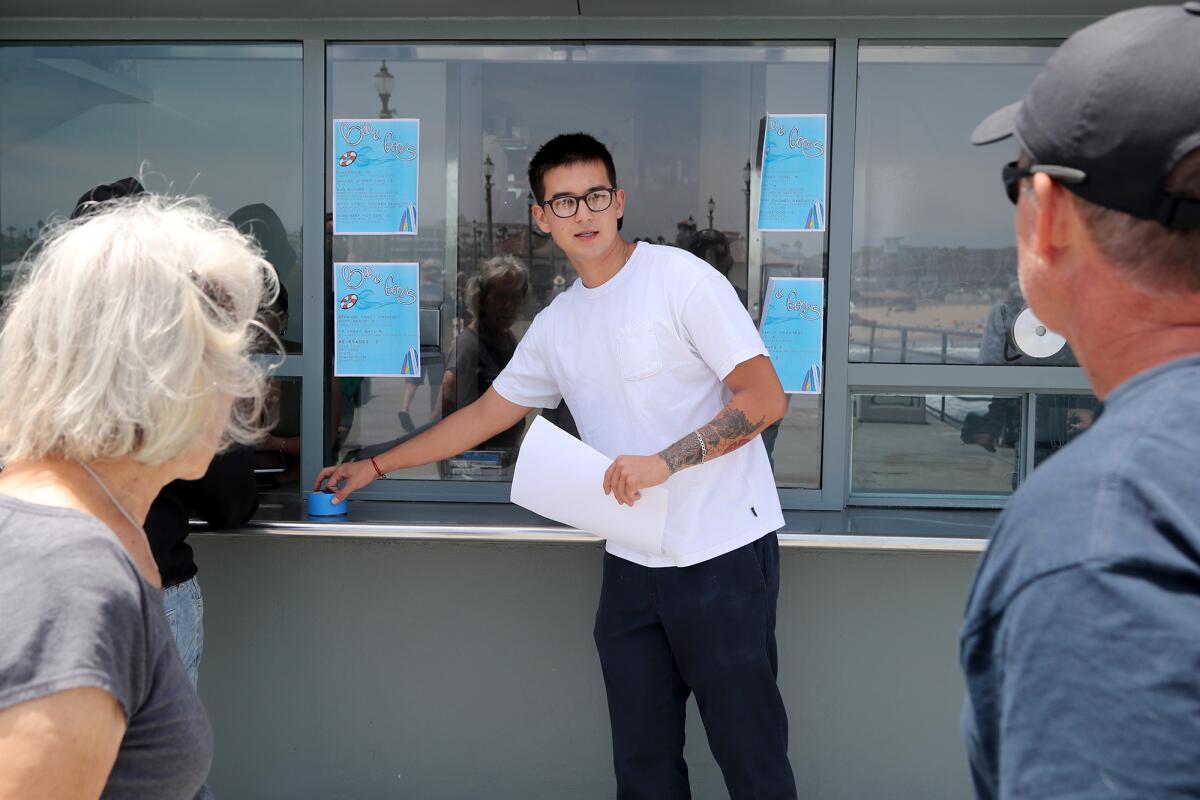 Jack Lee, 24, center, informs visitors that the grand opening for Bud & Gene's will be held next week as he tapes up menus.