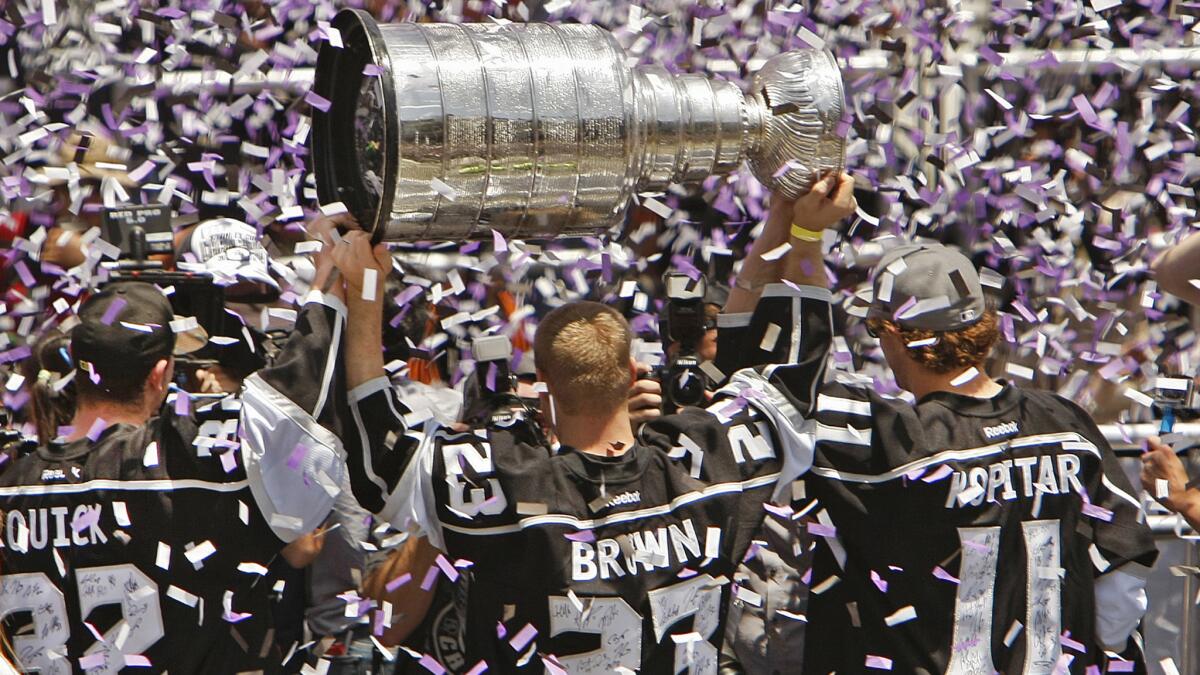 Kings teammates Jonathan Quick, left, Dustin Brown, center, and Anze Kopitar celebrate with the Stanley Cup outside Staples Center on June 16. The Kings have had their share of benefits from winning the Stanley Cup two times in three years.