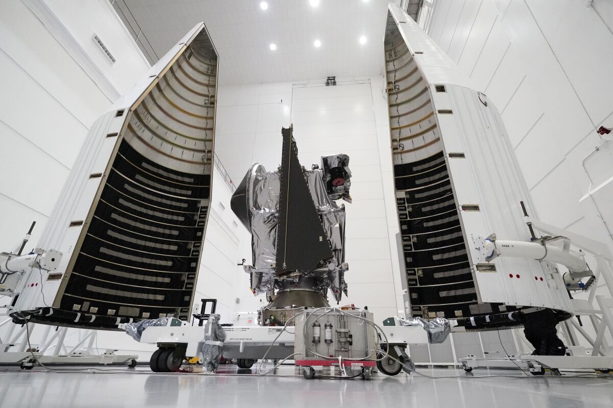 NASA's Lucy spacecraft and its housing are shown in a clean, well-lighted indoor space