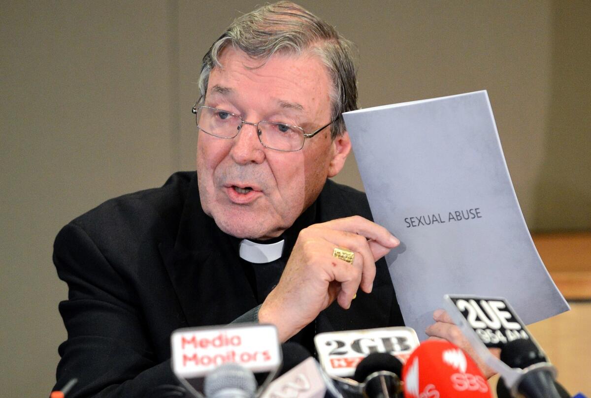 A file photo taken in 2012 shows Australia's Cardinal George Pell holding the response of the Catholic archdiocese to sexual abuse during a news conference in Sydney.