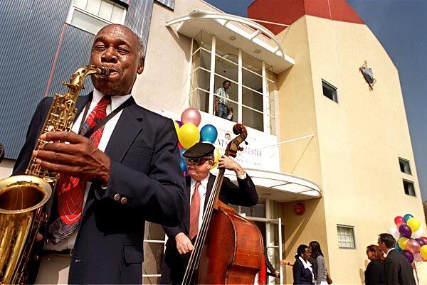 Buddy Collette, left, and Putter Smith, bass, perform at the grand opening of the City of Los Angeles Constituent Services Center at 8475 S. Vermont Ave. as members of the community enter for the first time. Collette used to live in the community and said he was happy to see old friends.