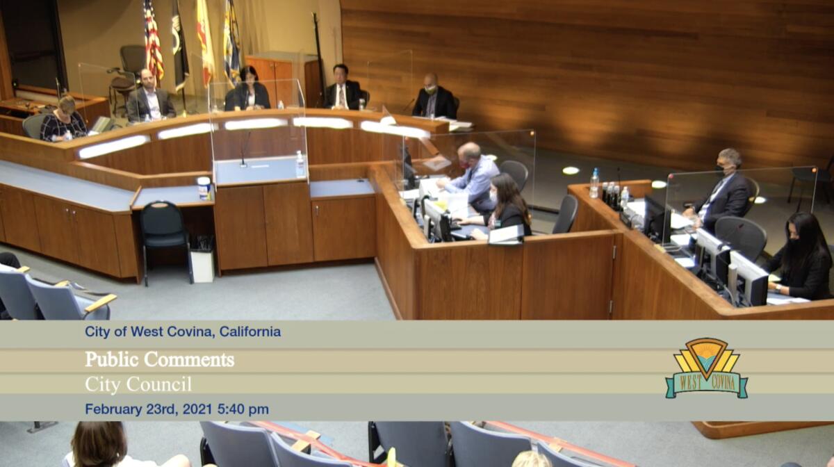 Council members attend a meeting, separated by clear partitions