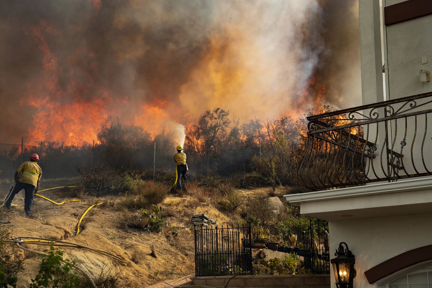 Firefighters battle to save a home from a wall off flames as the Holy fire continues to burn out of control in Lake Elsinore, Calif.