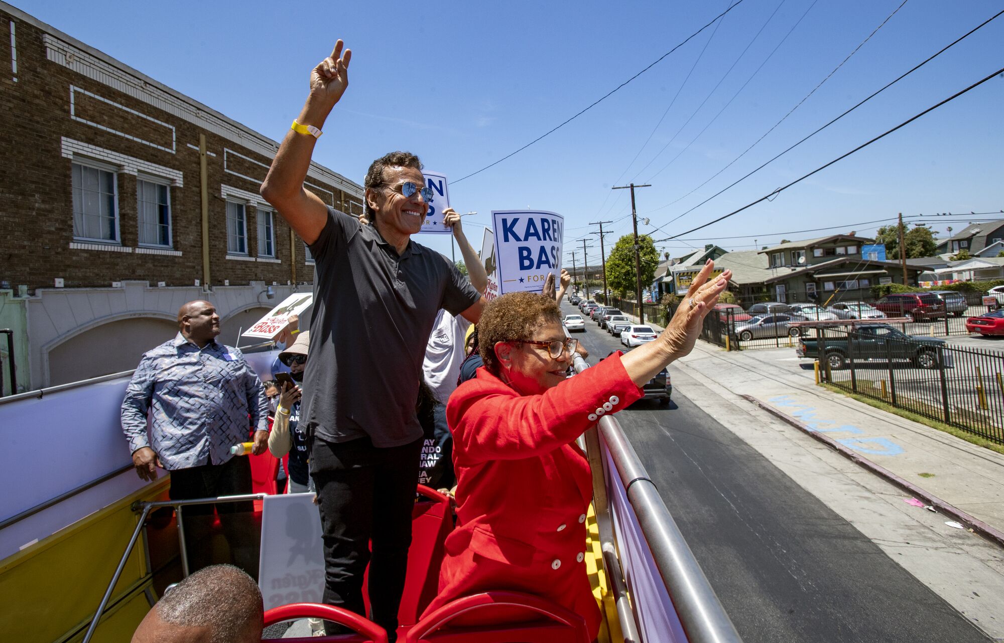 Rep. Karen Bass and former Mayor Antonio Villaraigosa wave to onlookers from a double-decker bus during a campaign event 