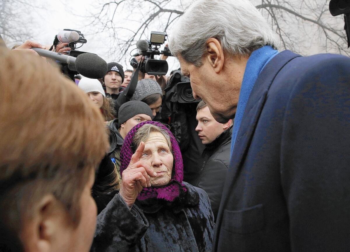 A Ukrainian woman speaks with U.S. Secretary of State John F. Kerry in Kiev as he visits a shrine to people killed during the recent political uprising.