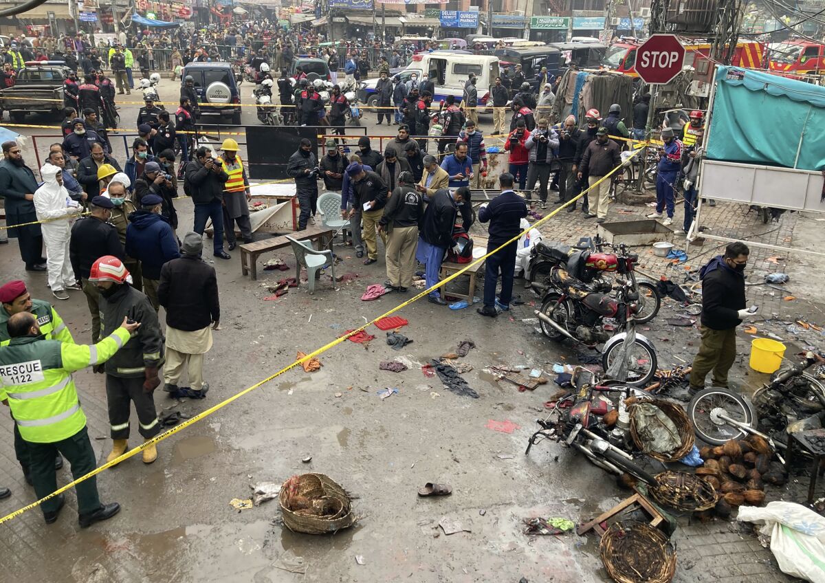 Police officials examine the site of bomb explosion, in Lahore, Pakistan, Thursday, Jan. 20, 2022. Police said the powerful bomb exploded in a crowded bazar in Pakistan’s second largest city of Lahore, killing several people and wounding dozens of others. (AP Photo/K.M. Chaudary)