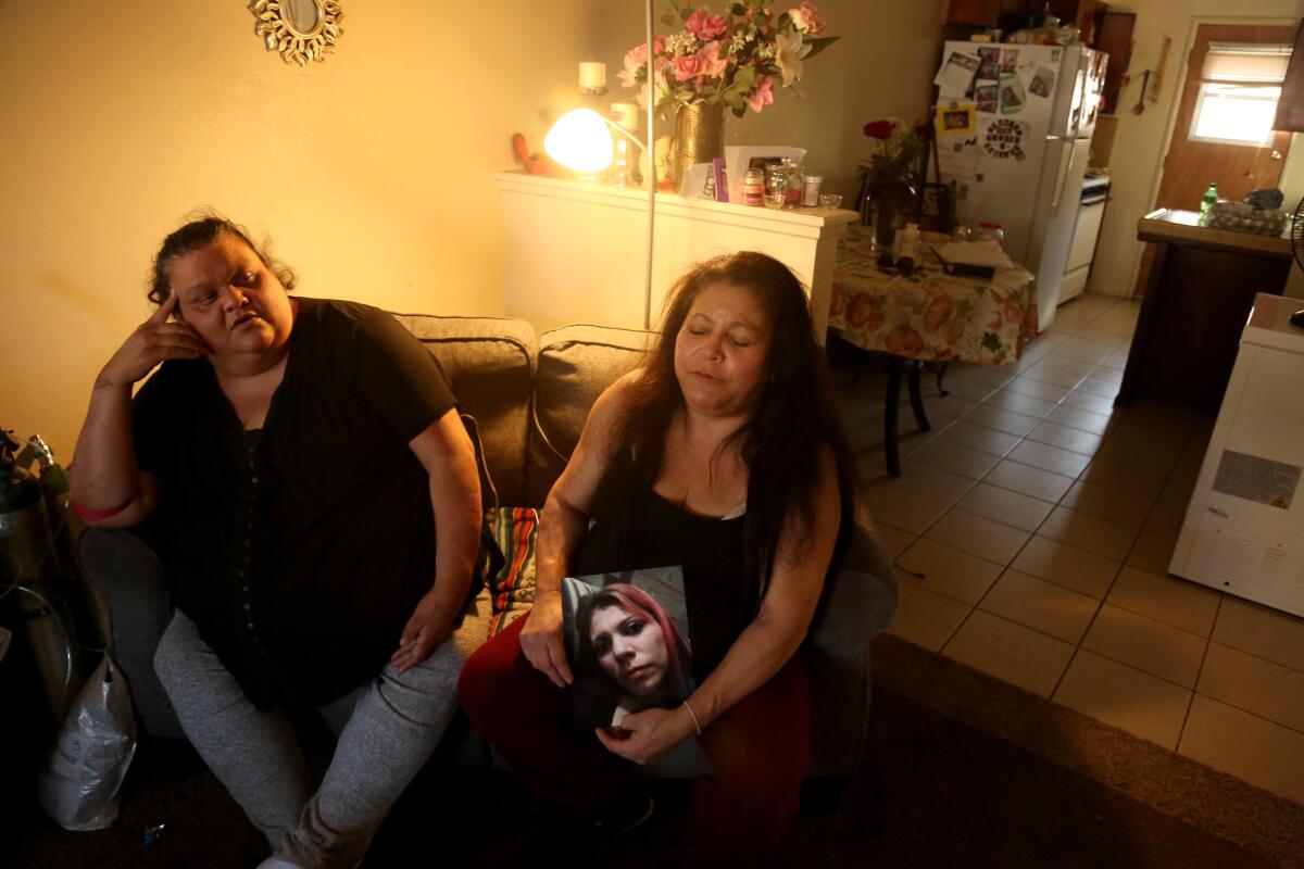 Tina Perez holds a photo of daughter Adora Perez while sitting next to Adora's aunt Sabrina Perez in Sabrina's home.