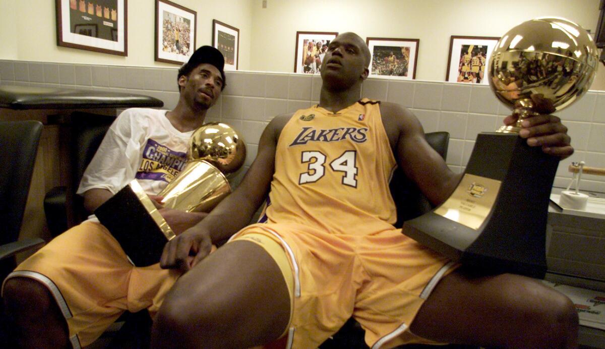Kobe Bryant and Shaquille O'Neal, holding the NBA and MVP trophies, won their first title together in 2000.