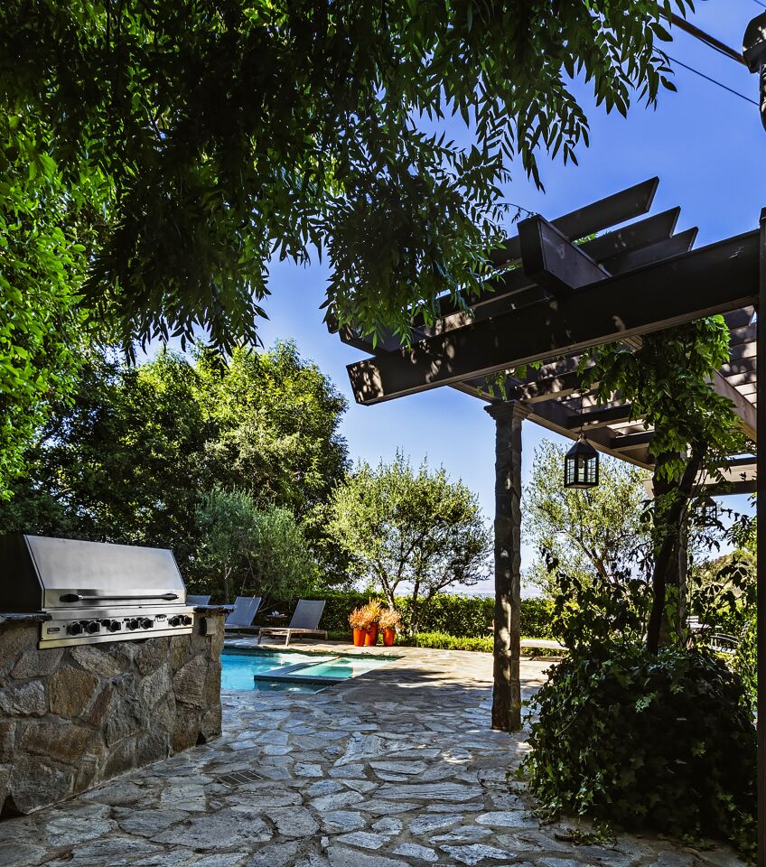 Trees shade the outdoor grill and pool area.