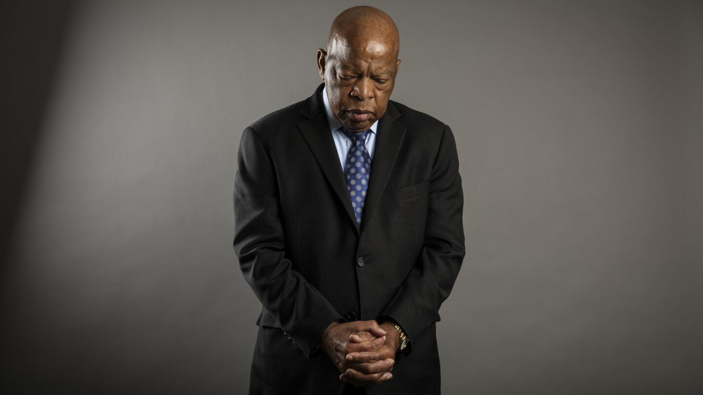 John Lewis clasps his hands and bows his head while posing for a portrait
