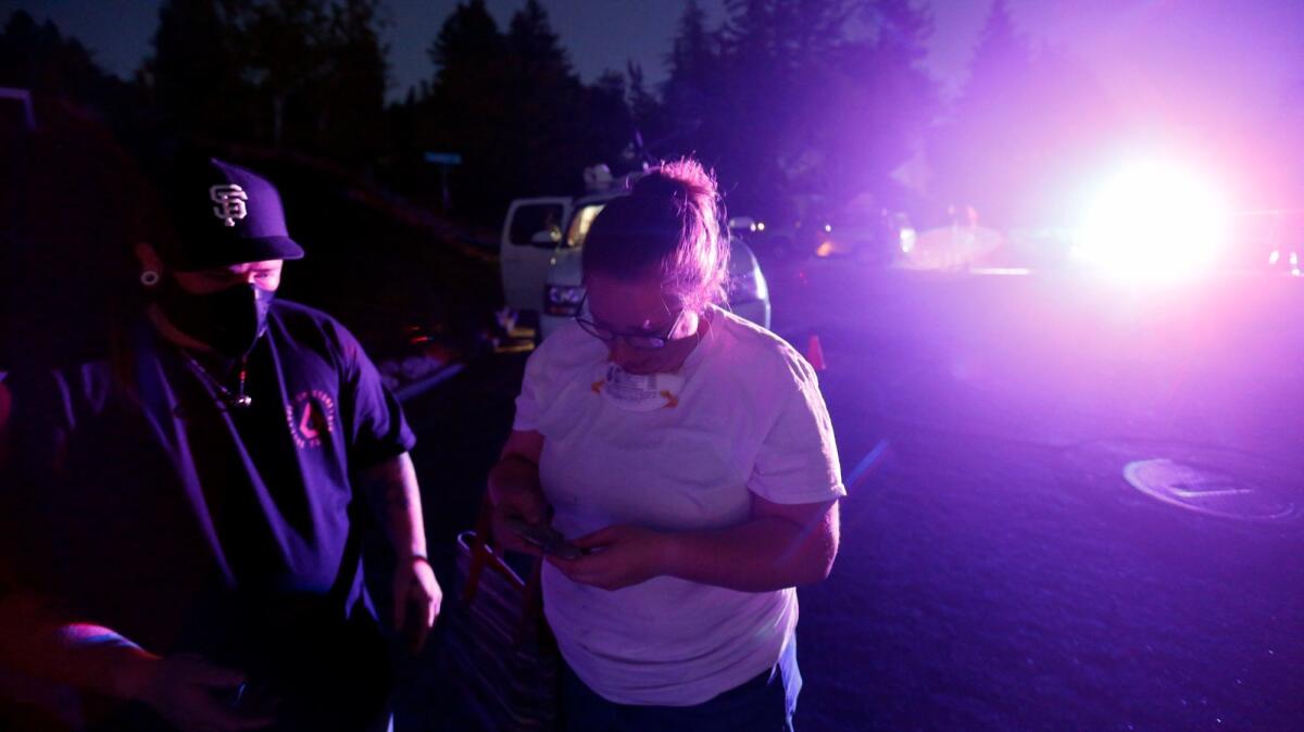 Jaiden Campbell, left, looks at her partner, Kimberly Flinn, holding a ceramic butterfly salvaged from their home in Santa Rosa.