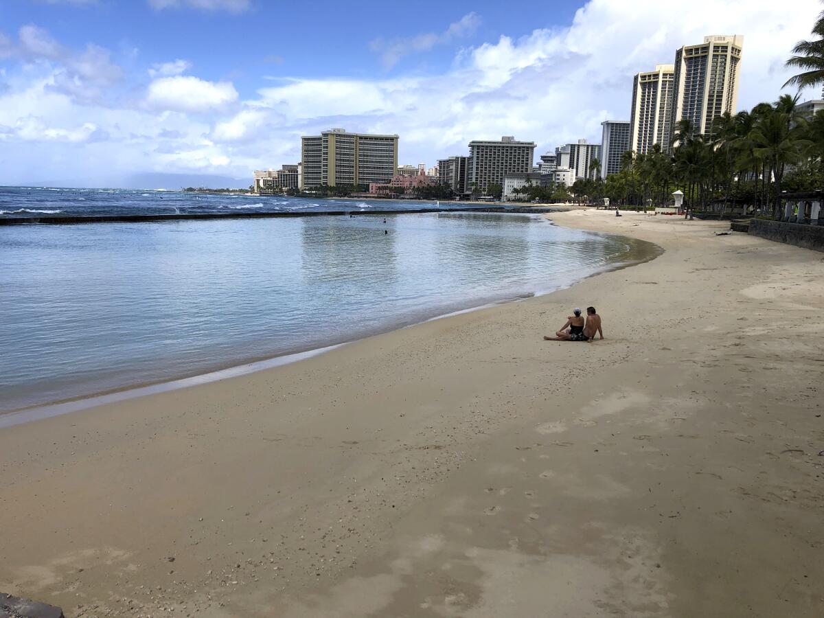 A couple sits on an empty section of Waikiki Beach in Honolulu in March.