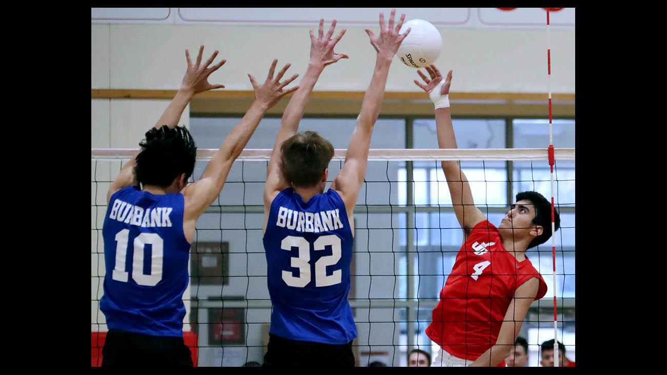 Burroughs High School volleyball player #4 Diego Rosal puts the ball over #10 Jonathan Valmonte, left, and #32 Luca Bily, center, in home game vs. Burbank High School, in Burbank on Friday, March 30, 2018.