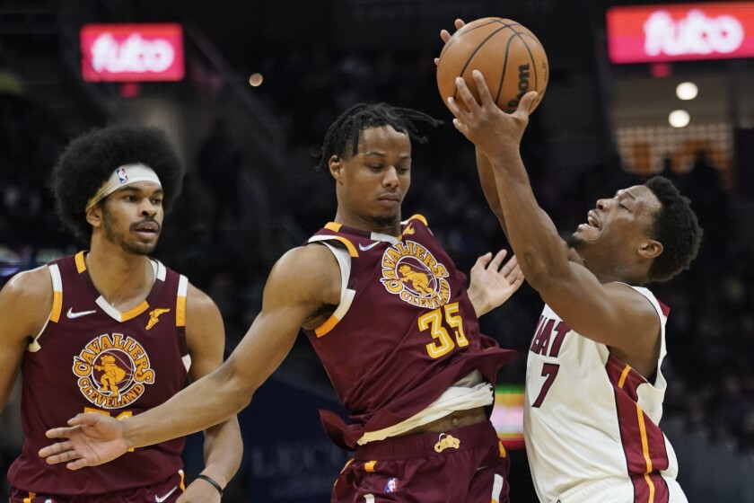 Miami Heat's Kyle Lowry (7) drives against Cleveland Cavaliers' Isaac Okoro (35) in the second half of an NBA basketball game, Monday, Dec. 13, 2021, in Cleveland. Cavaliers' Jarrett Allen, left, watches. (AP Photo/Tony Dejak)