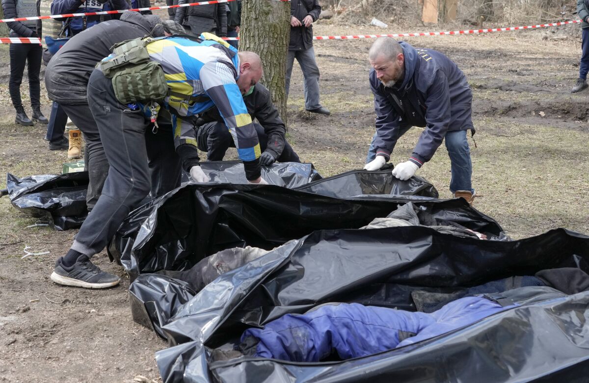 Volunteers collect bodies of murdered civilians, in Bucha, close to Kyiv, Ukraine, Monday, April 4, 2022. Russia is facing a fresh wave of condemnation after evidence emerged of what appeared to be deliberate killings of civilians in Ukraine. (AP Photo/Efrem Lukatsky)