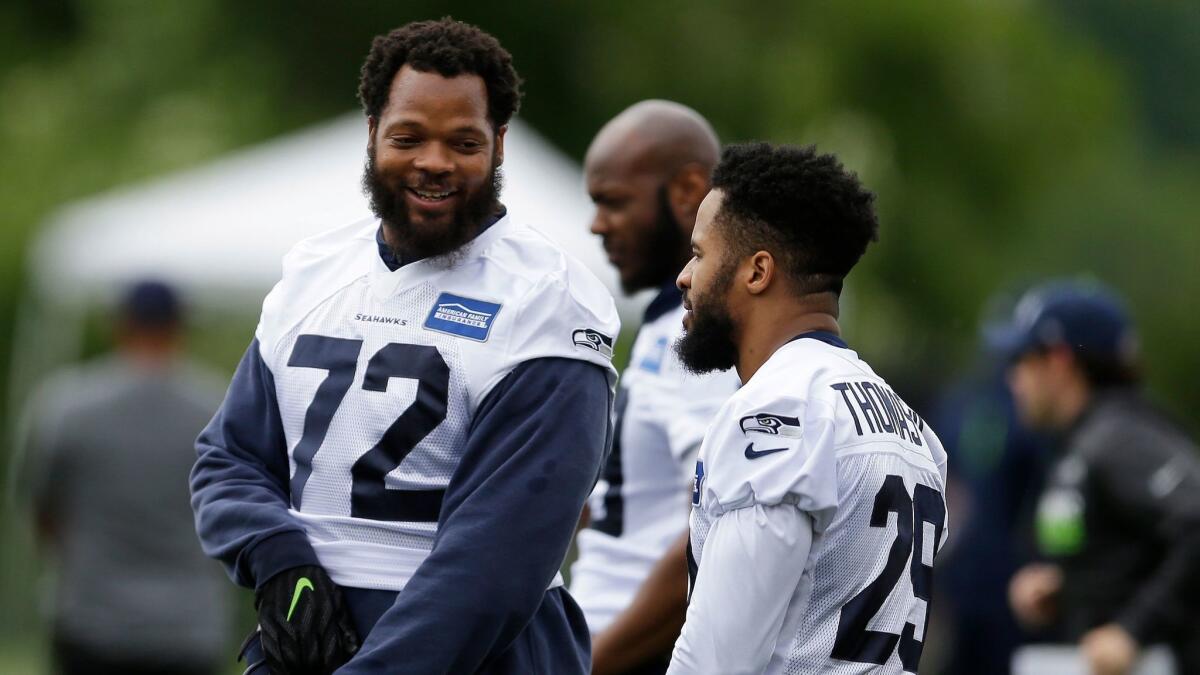 Seattle Seahawks defensive end Michael Bennett, above left at a recent football practice, is co-writing a new book, "How to Make White People Uncomfortable," to be published next year.