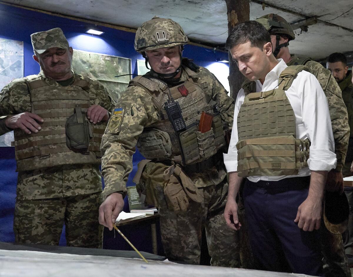 Ukrainian President Volodymyr Zelensky, right, is briefed by a serviceman during a visit to war-torn eastern Ukraine in October.