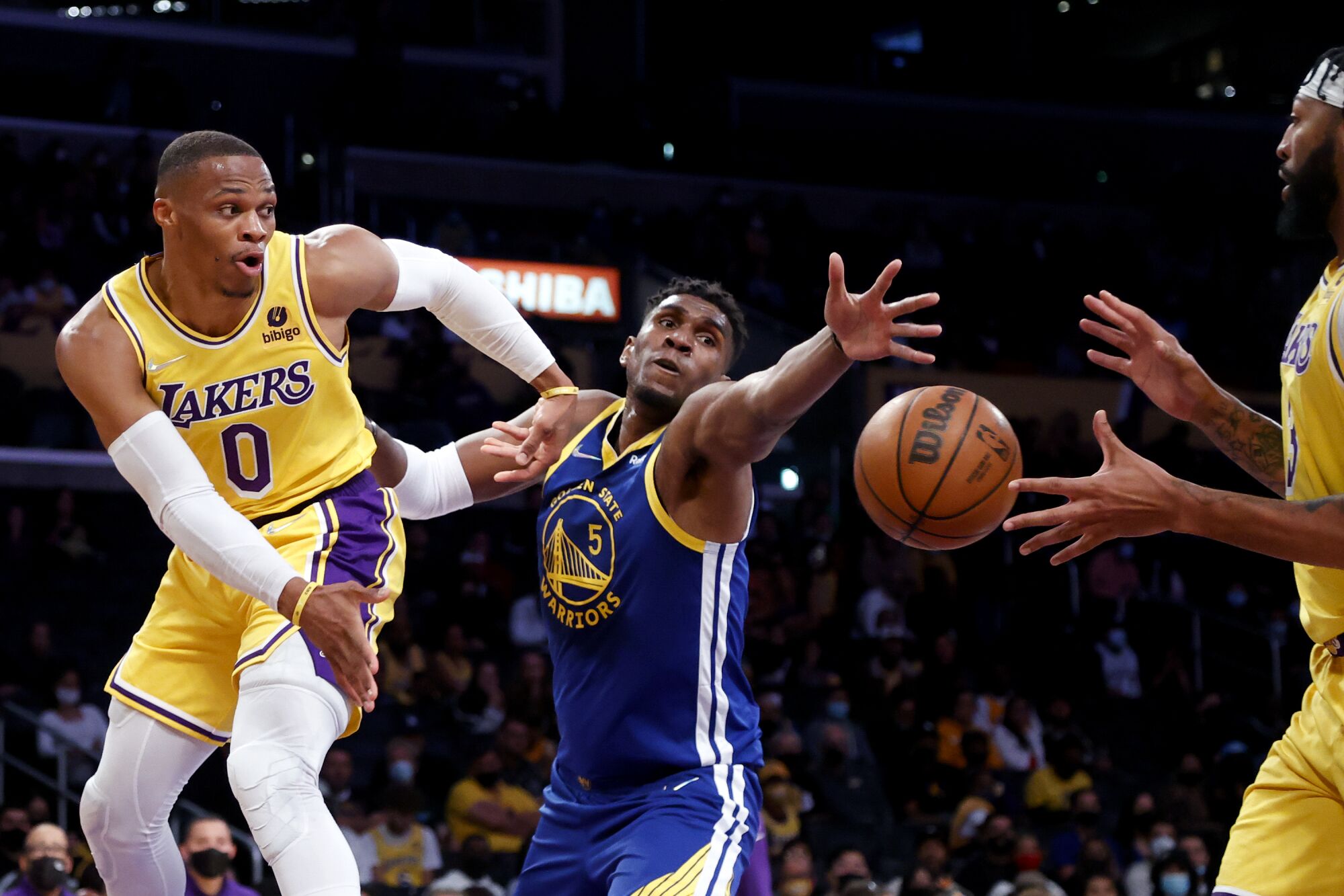 Lakers guard Russell Westbrook passes around Warriors center Kevon Looney to teammate Anthony Davis.