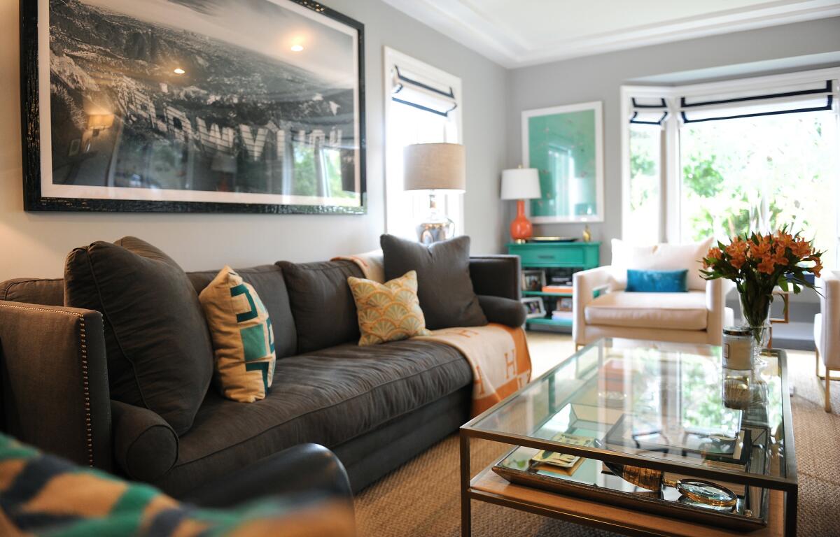 In the living room, bordered window shades by Neal Bernardino and upholstered armchairs add sophistication to a room with bright splashes of color.