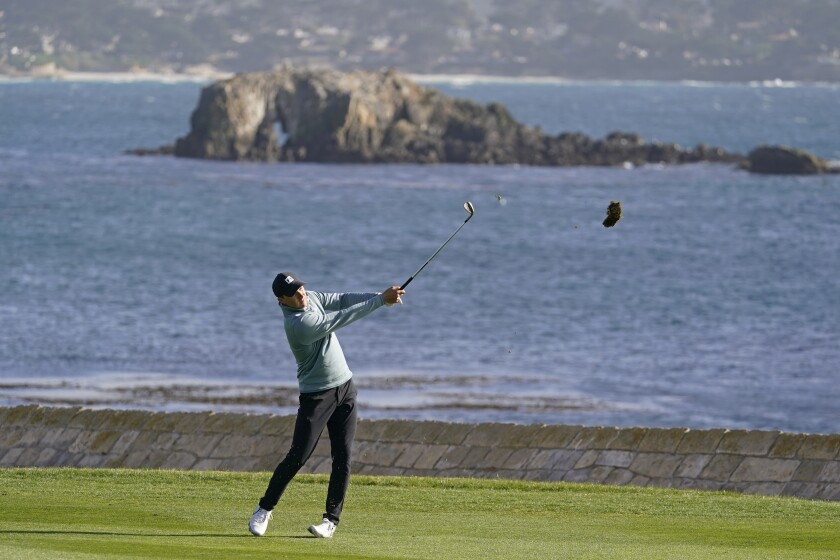 Jordan Spieth hits his approach shot to the 18th green at Pebble Beach Golf Links on Feb. 13, 2021.