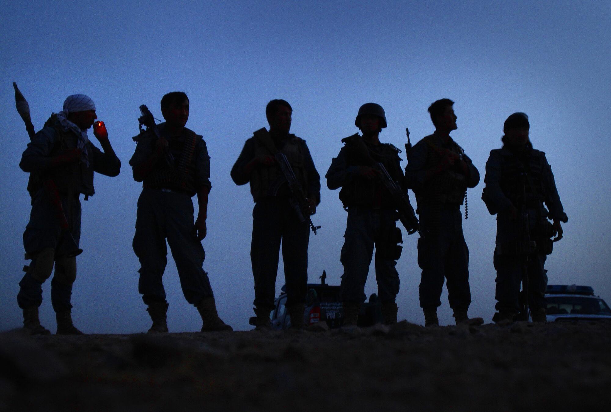 A line of armed officers silhouetted in the dawn