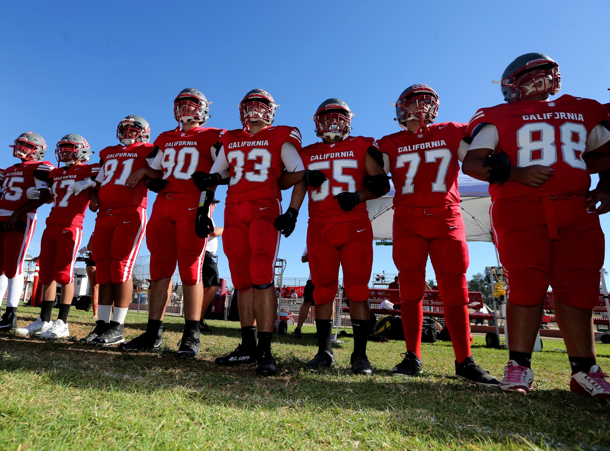 CSDR football players stand stand along the sideline with arms locked together before the game Saturday.