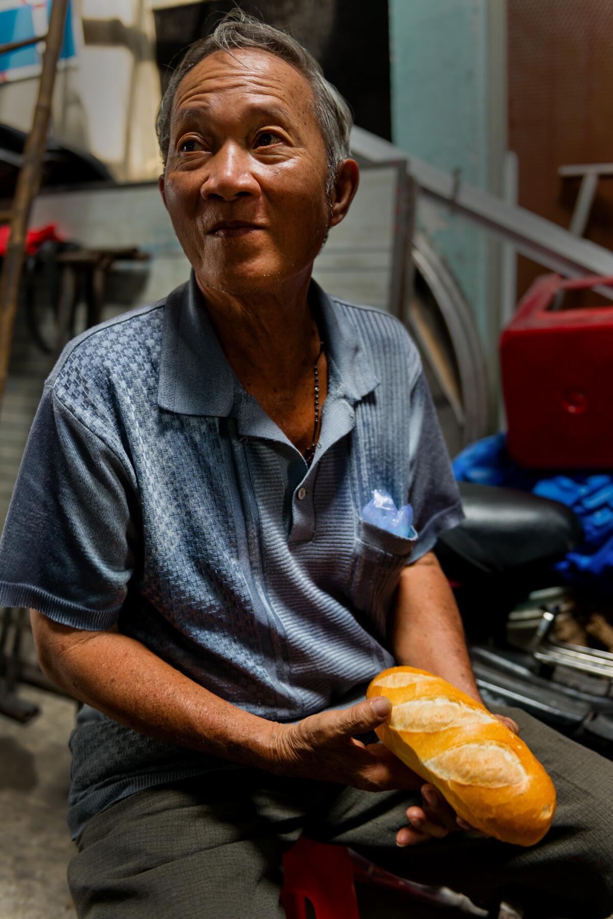 Baker Van No Nguyen talks about banh mi bread while holding a loaf at his Ho Chi Minh City bakery.