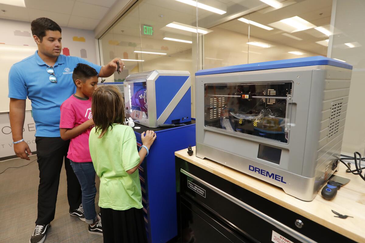 Aureo Tellez, a program manager, shows children a 3-D printer in the Maker Space room at the newly renovated Boys & Girls Club of Costa Mesa on Tuesday.