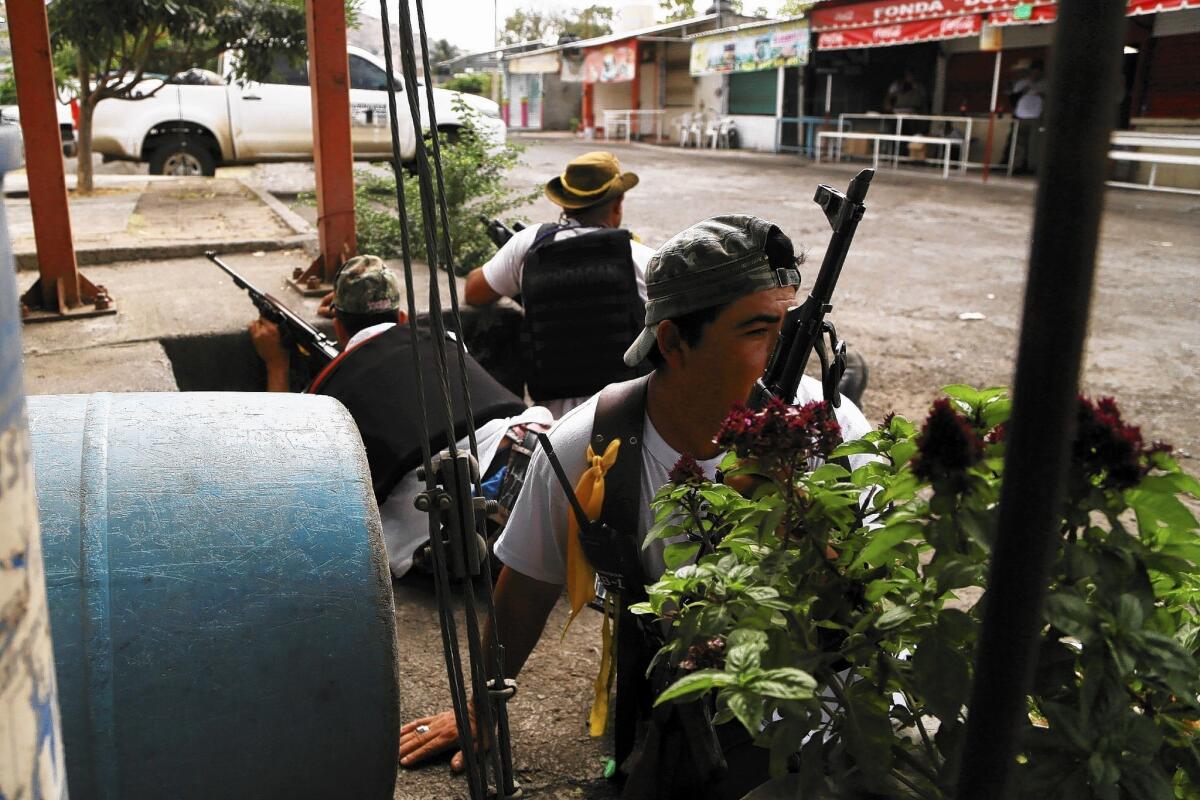 Members of a peasant group battling a drug cartel take their positions after arriving in the town of Nueva Italia in Mexico's Michoacan state. The federal government has called on such groups to disarm and go home.