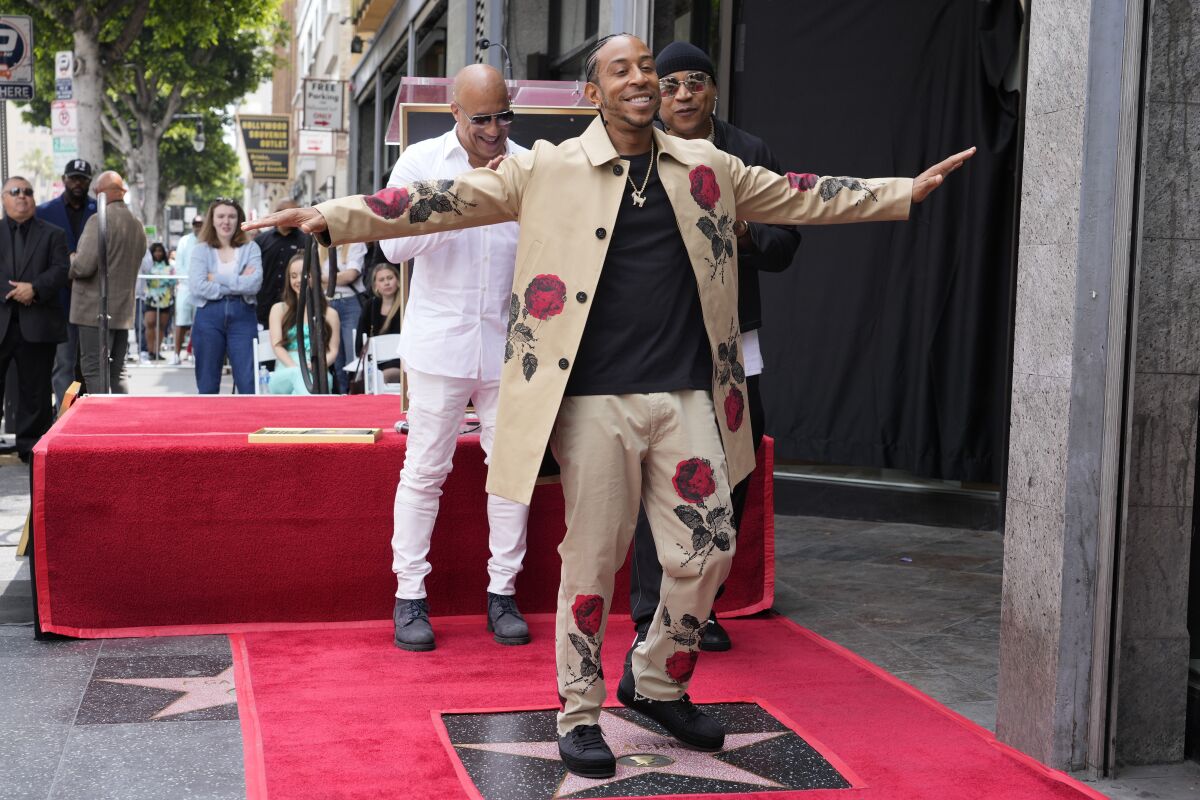 Ludacris dances atop his Hollywood Walk of Fame star with his arms outstretched in front of Vin Diesel and LL Cool J