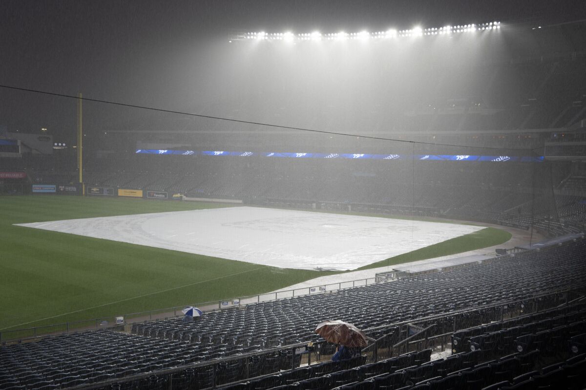 A few fans sit through a deluge at Kauffman Stadium that forced a rain delay in a baseball game between the Kansas City Royals and the Chicago White Sox, Friday, Sept. 3, 2021 in Kansas City, Mo. (AP Photo/Reed Hoffmann)