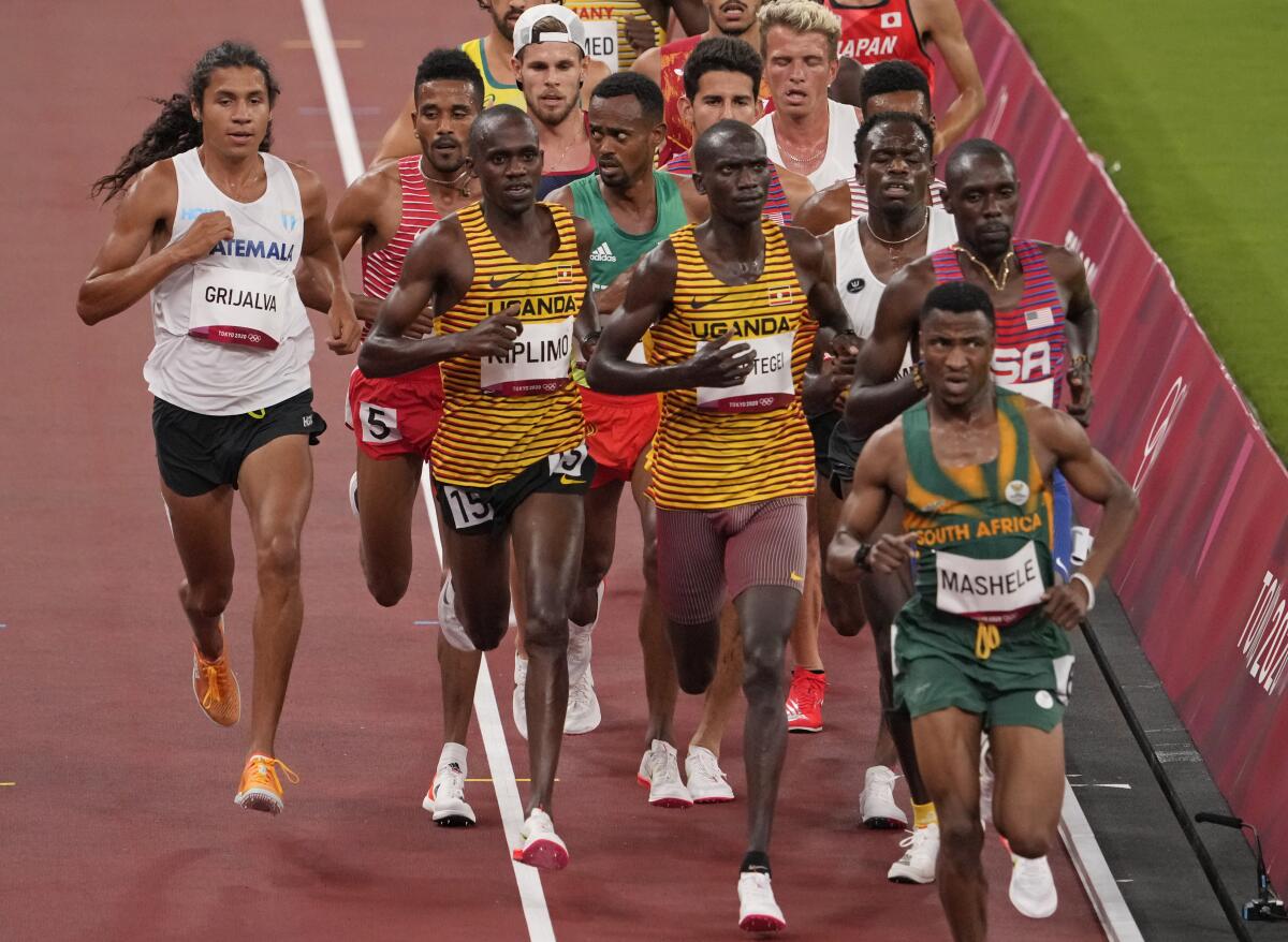 Luis Grijalva of Guatemala, left, competes in a men's 5,000-meter qualifying heat.