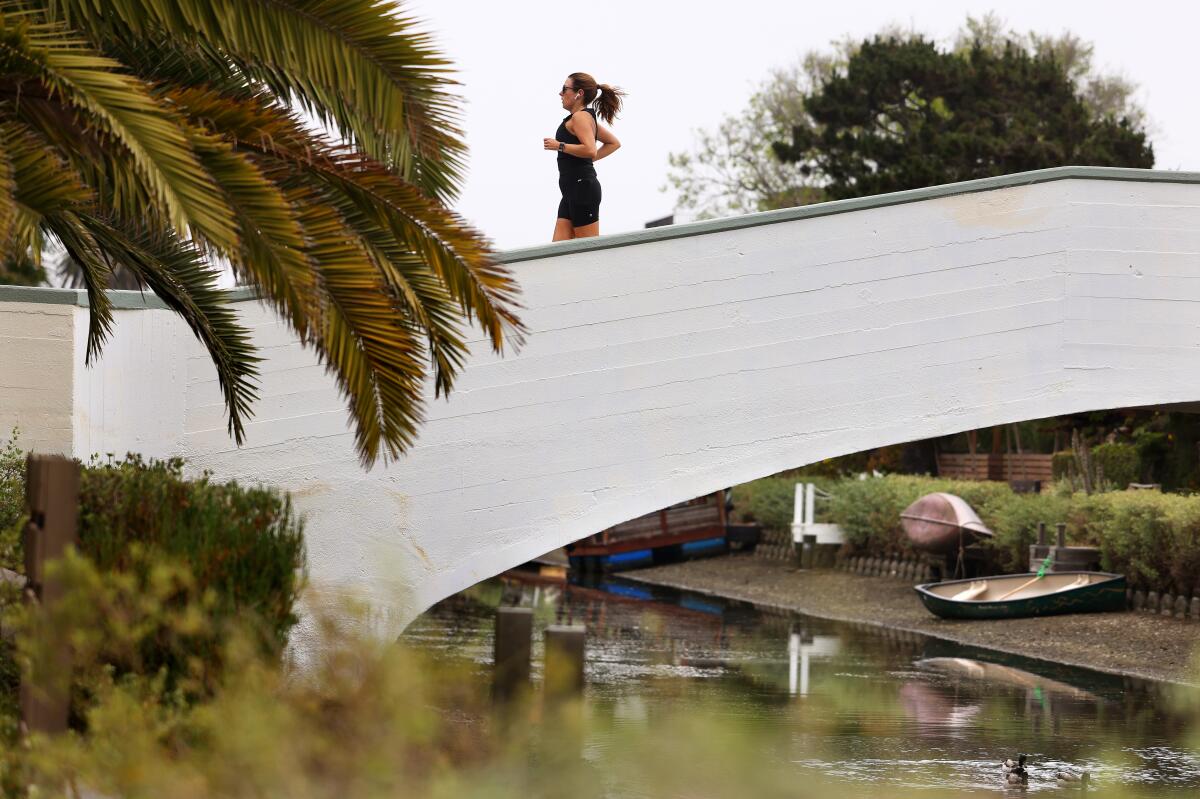 A runner crosses over a bridge at the Venice Canals.