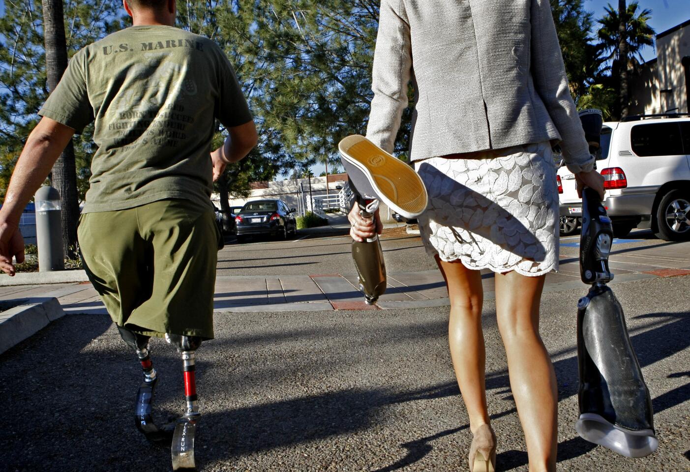 After a workout at Naval Medical Center San Diego, Marine Staff Sgt. Mark Zambon and wife Marta walk to their car. She carries his regular walking legs while he uses athletic prosthetic legs.