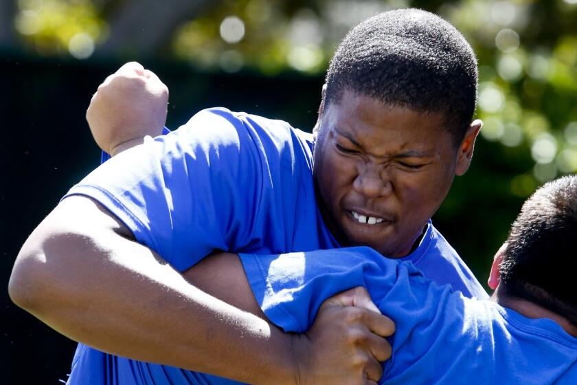 Windward offensive lineman Roy Hemsley tackles a teammate during a practice. He is expected to enroll at USC next month.