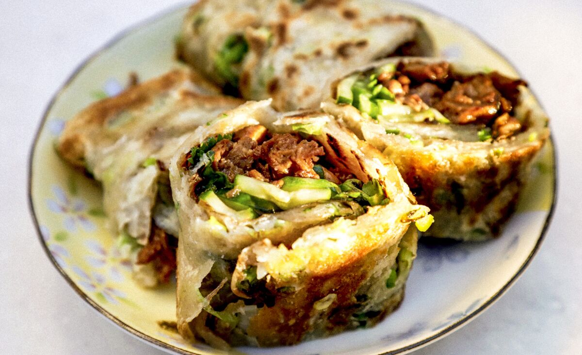 A plate with four pieces of rolled dough with a savory filling.