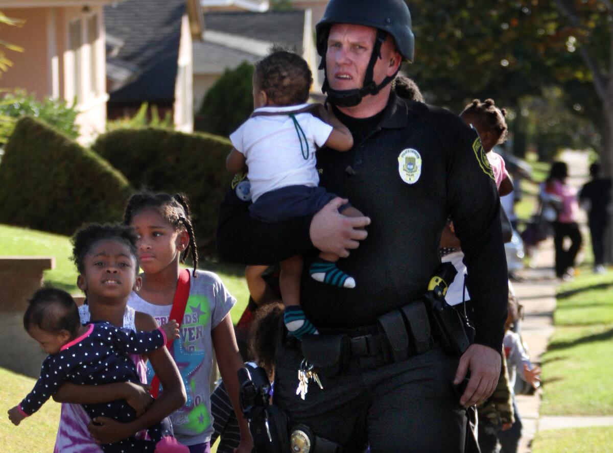Inglewood police officer Joey Zeller leads children to safety from the neighborhood where two other police officers were injured during a hostage standoff.