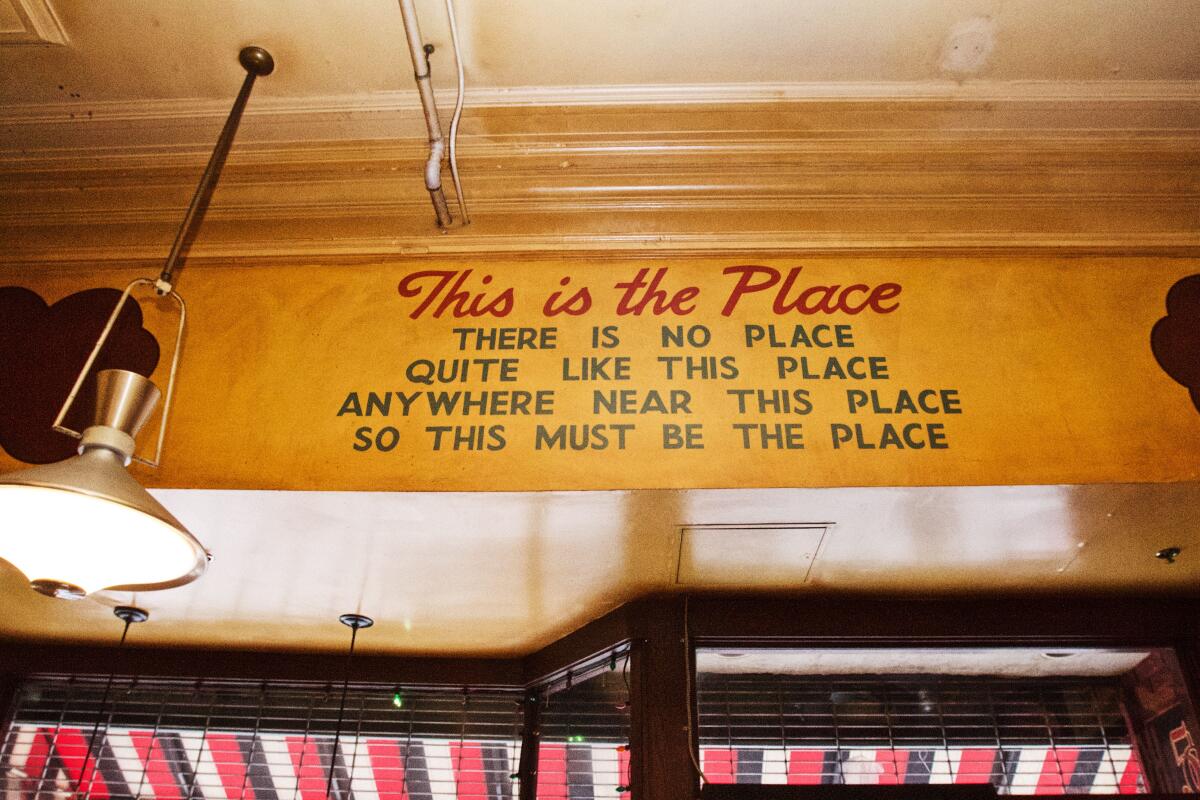 A sign that says “This is the place, there is no place / quite like this place anywhere near this place" above a door