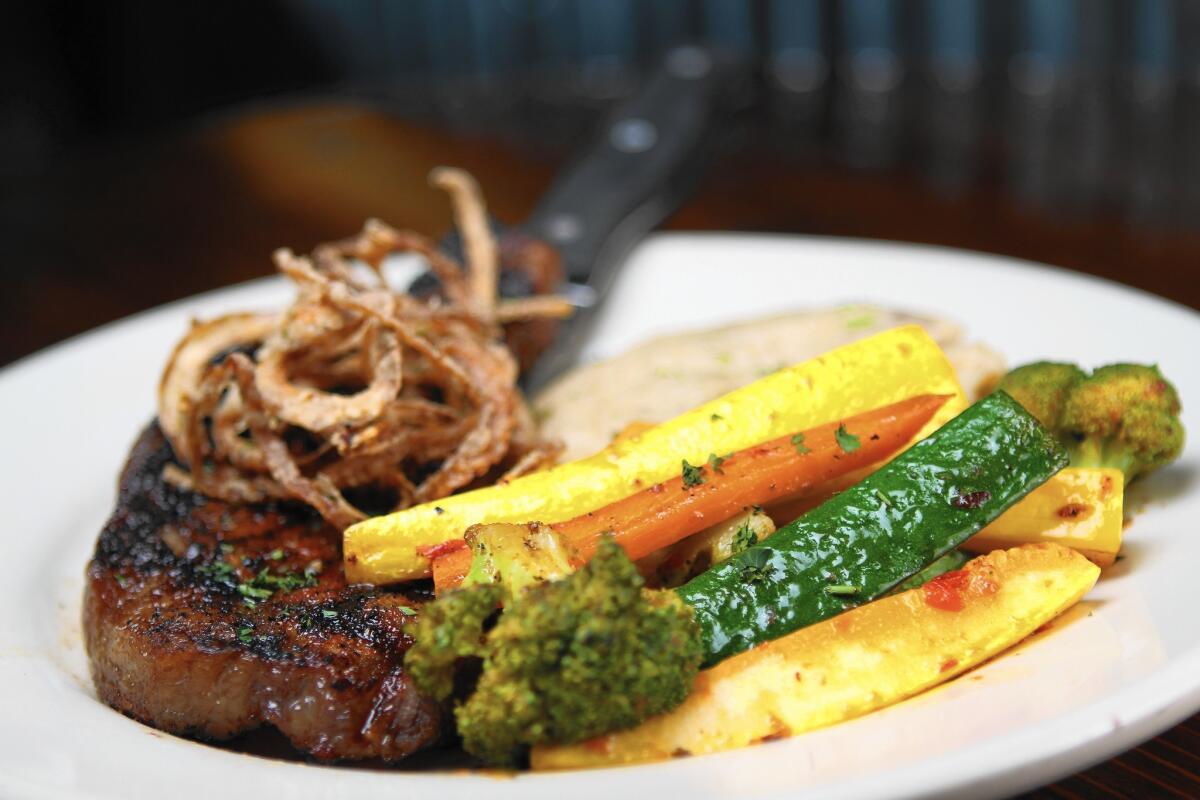 A grilled New York steak, marinated and topped with crispy sweet onions and a side of mashed potatoes and sauteed vegetables at the Hangar Grille in Burbank.