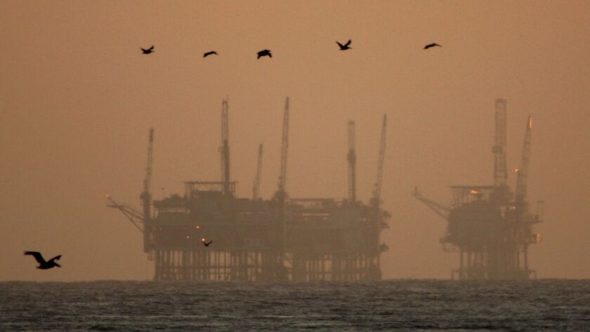 California brown pelicans fly near offshore oil rigs after sunset on July 21, 2009 near Santa Barbara, California.