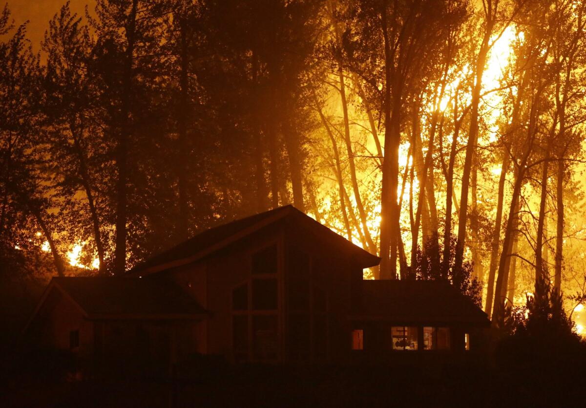 A wildfire burns behind a home in Twisp, Wash.