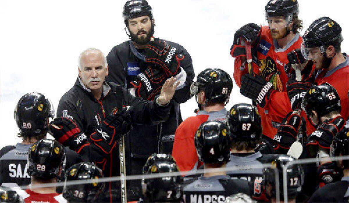 Chicago Blackhawks head coach Joel Quenneville, left, talks to his players at the end practice Tuesday before Game 1 of the Stanley Cup Final against the Boston Bruins on Wednesday.