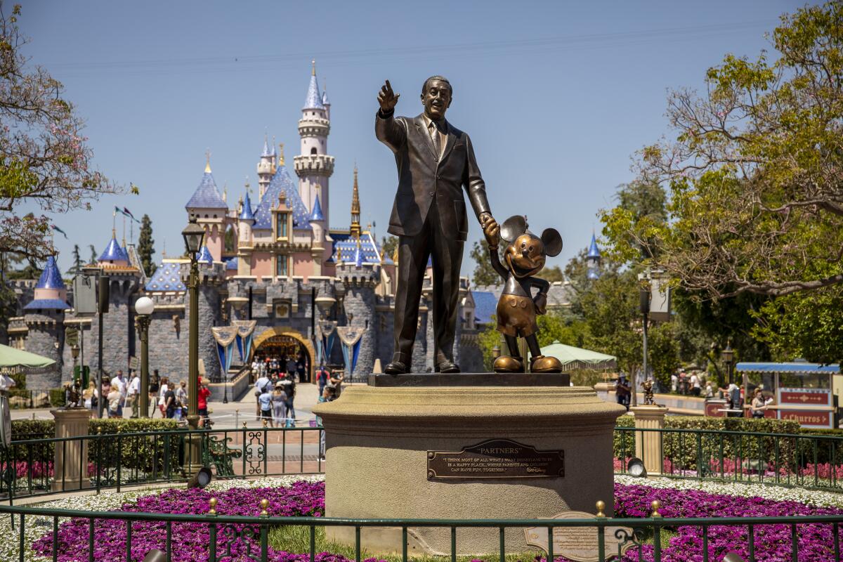 A statue of Walt Disney holding hands with Mickey Mouse at Disneyland. 