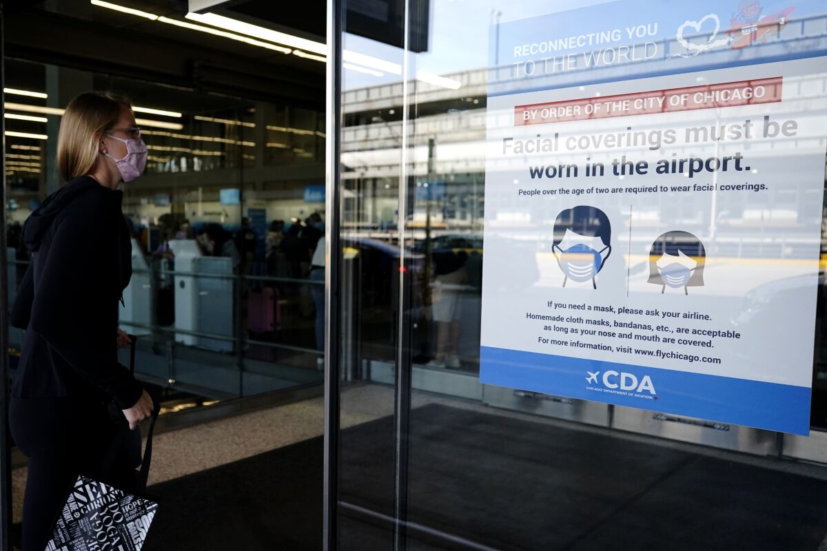 In this July 2, 2021 photo, a traveler walks in Terminal 3 as a sign stating face coverings are required is displayed at O'Hare International Airport in Chicago. The leading U.S. airlines say that the rise in COVID-19 cases is hurting ticket sales and pushing back the recovery of the travel industry. American, United, Delta, Southwest and others reported setbacks in regulatory filings Thursday, Sept. 9. (AP Photo/Nam Y. Huh)